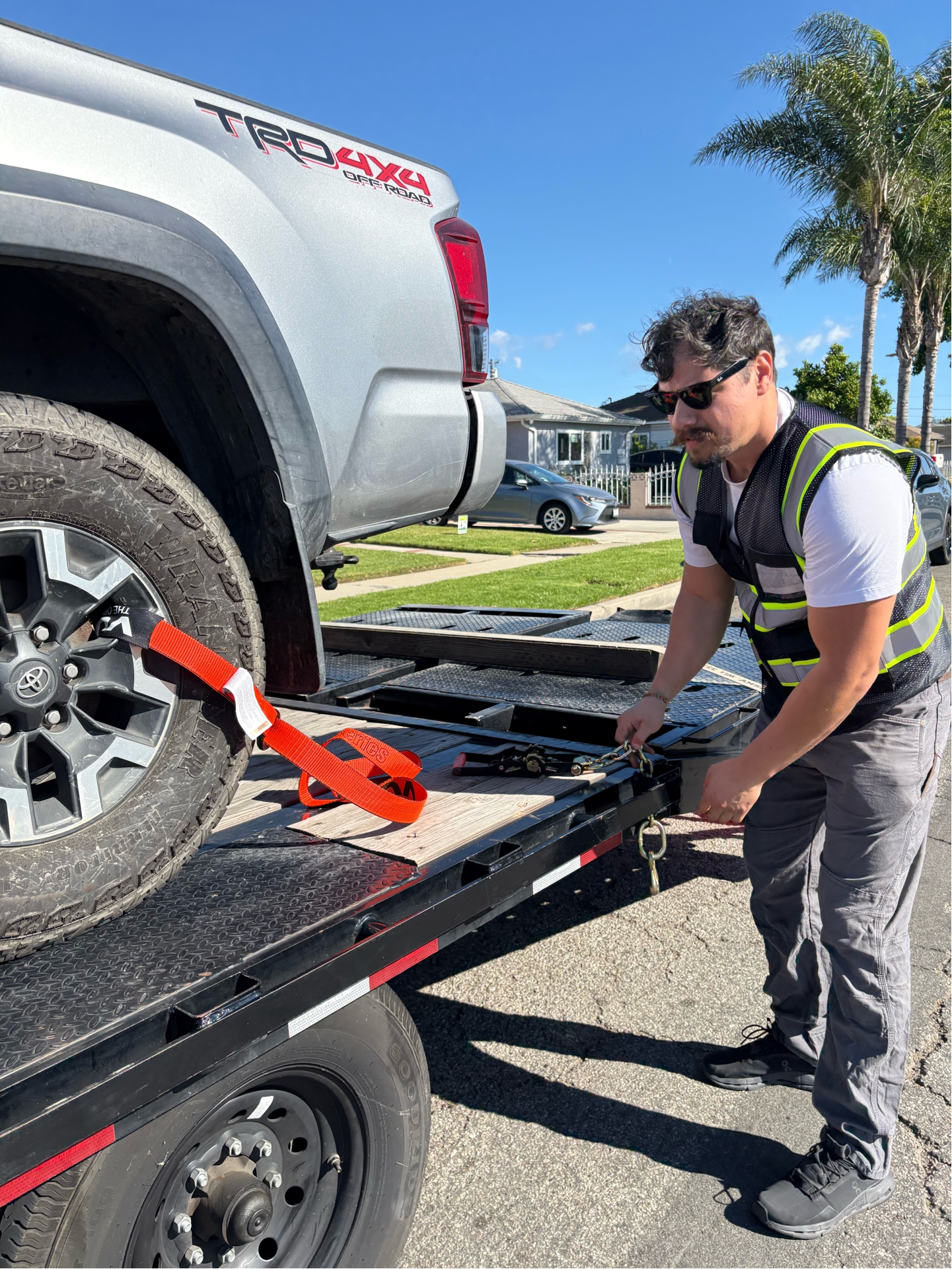 Owner securing a vehicle with professional tie-down straps on the flatbed