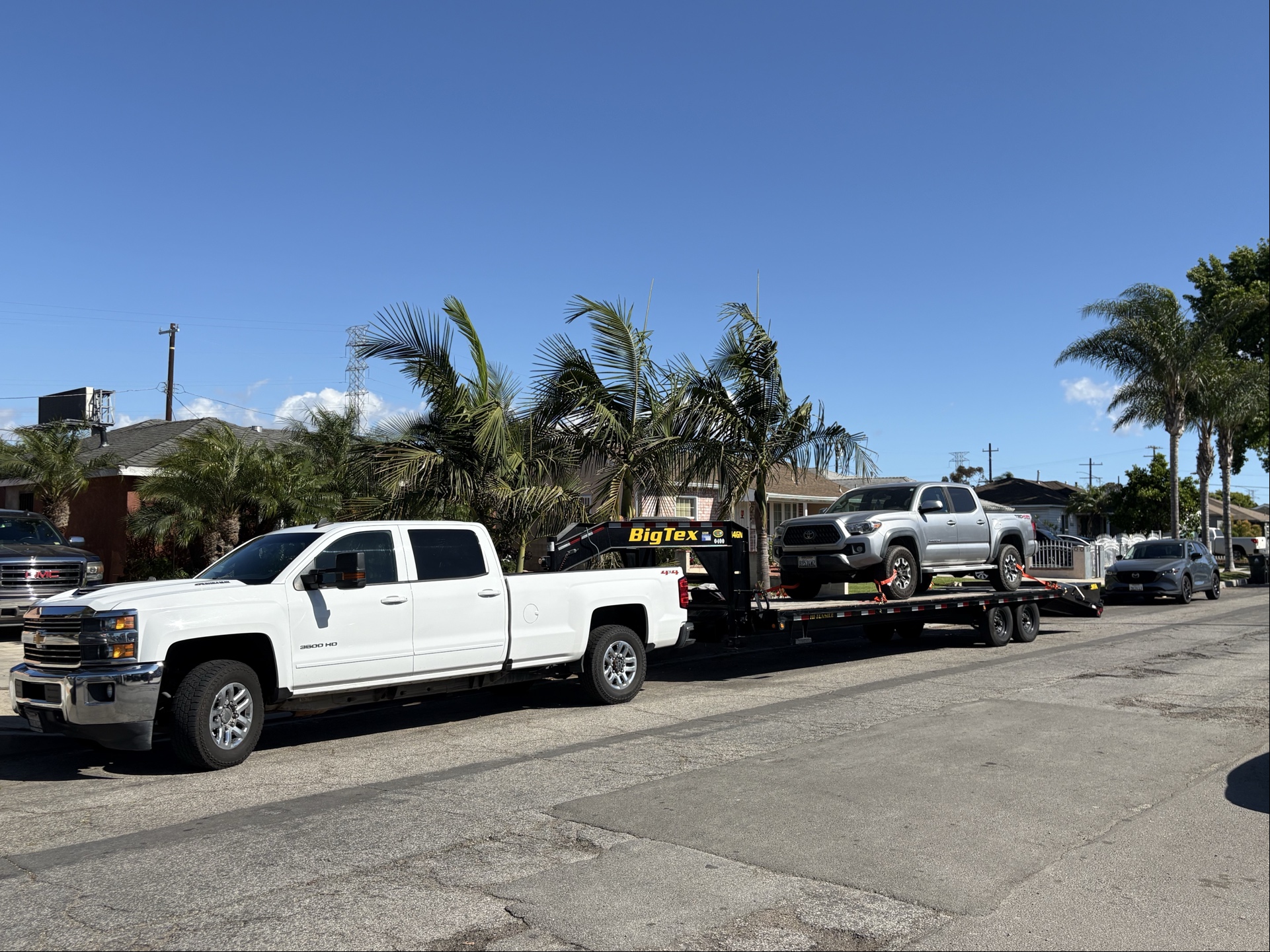 Pacific Titan Logistics - White Chevrolet Silverado 3500 HD with Big Tex flatbed trailer transporting a vehicle
